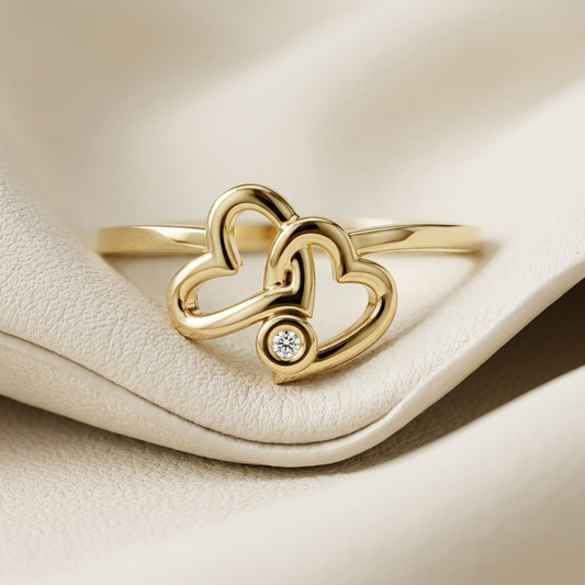 Yellow gold ring with intertwined heart design and diamond accent
Romantic double heart gold ring featuring a round diamond
Elegant interlocking heart ring in polished yellow gold
Modern gold love ring with linked heart motif and diamond
Fine jewelry heart ring displayed on soft ivory surface
Delicate yellow gold ring with sculptural double heart centerpiece
Luxury intertwined heart ring with bezel set diamond accent
Contemporary gold ring featuring overlapping open heart shapes
Polished yellow gold romanti